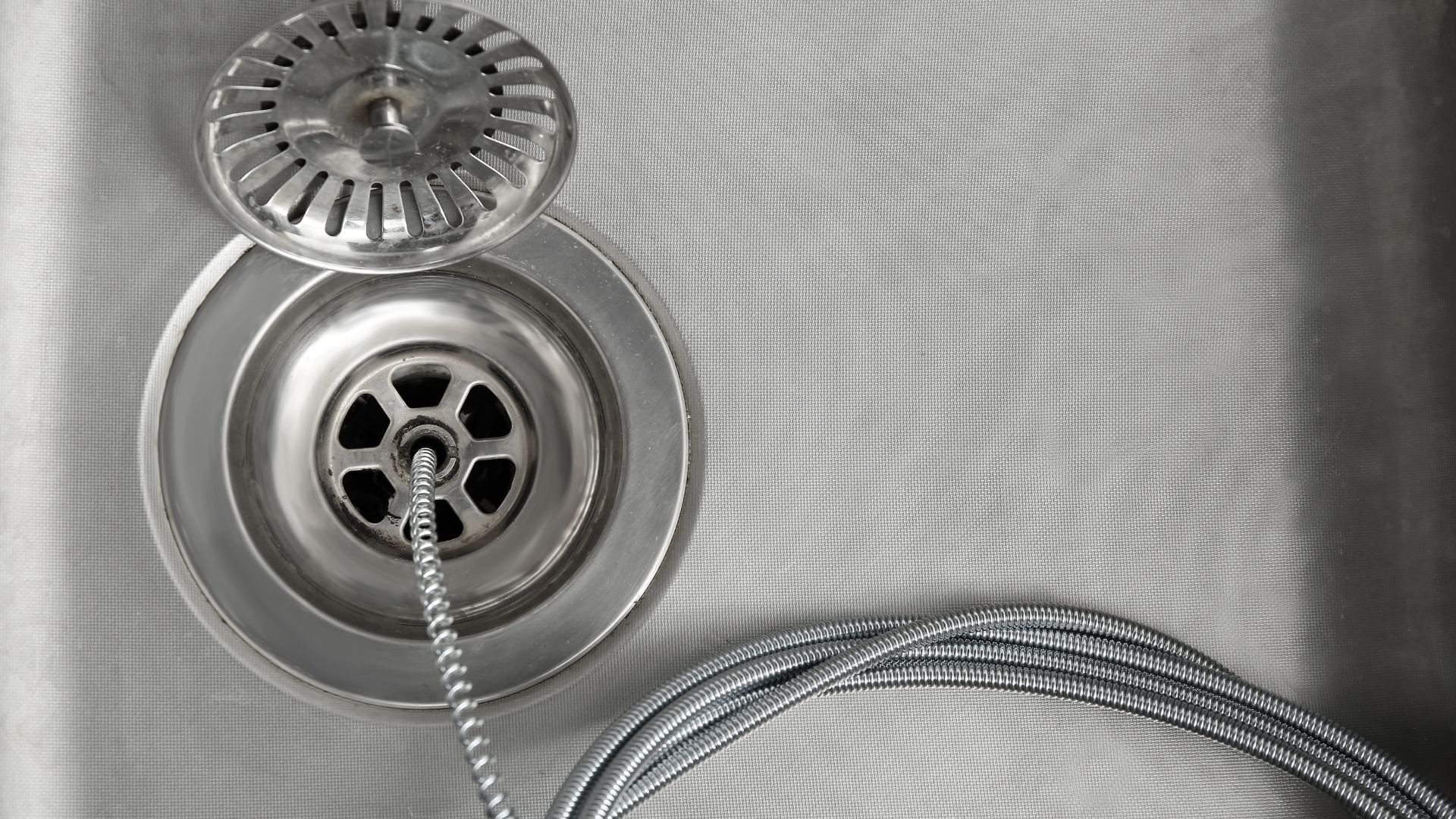 Overhead view of metal wall outlet with flexible electrical cord attached to white wall