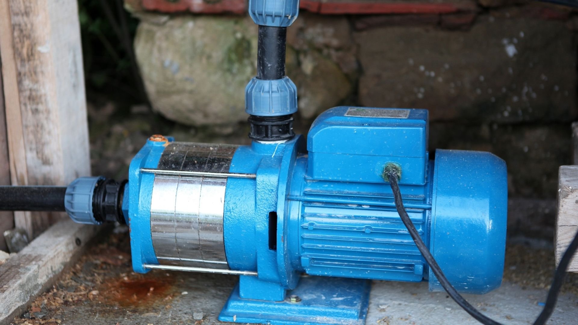 Blue electric water pump with motor and black cable in industrial setting