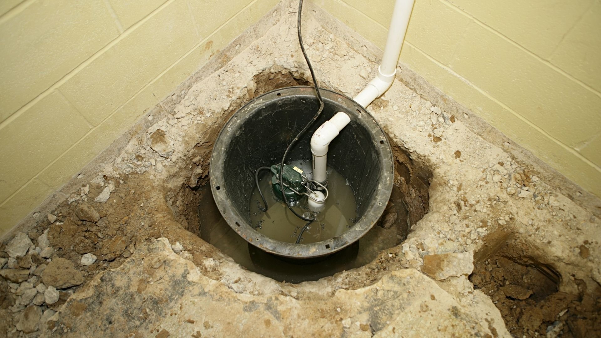 Sump pump pit with float switch installed in unfinished basement