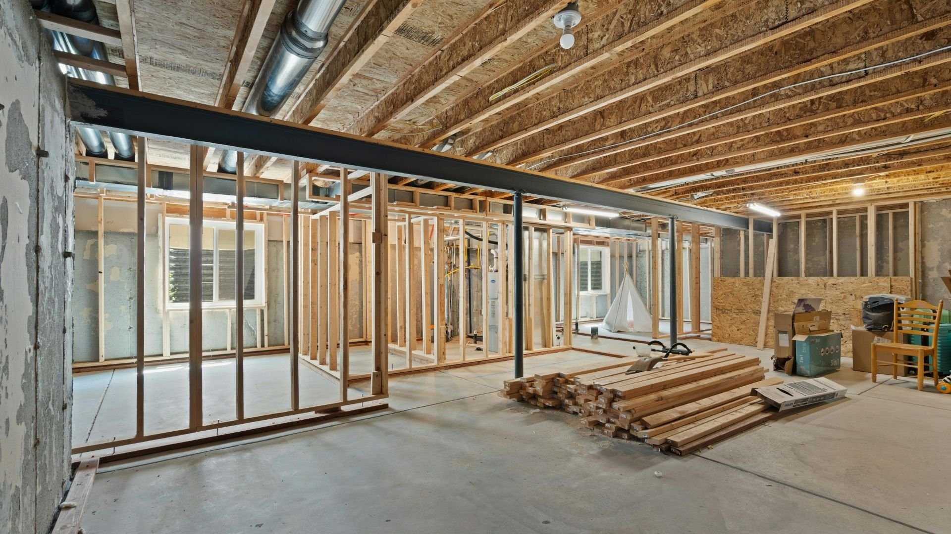 Under-construction open floor plan with exposed wood framing, building materials, and glass partitions