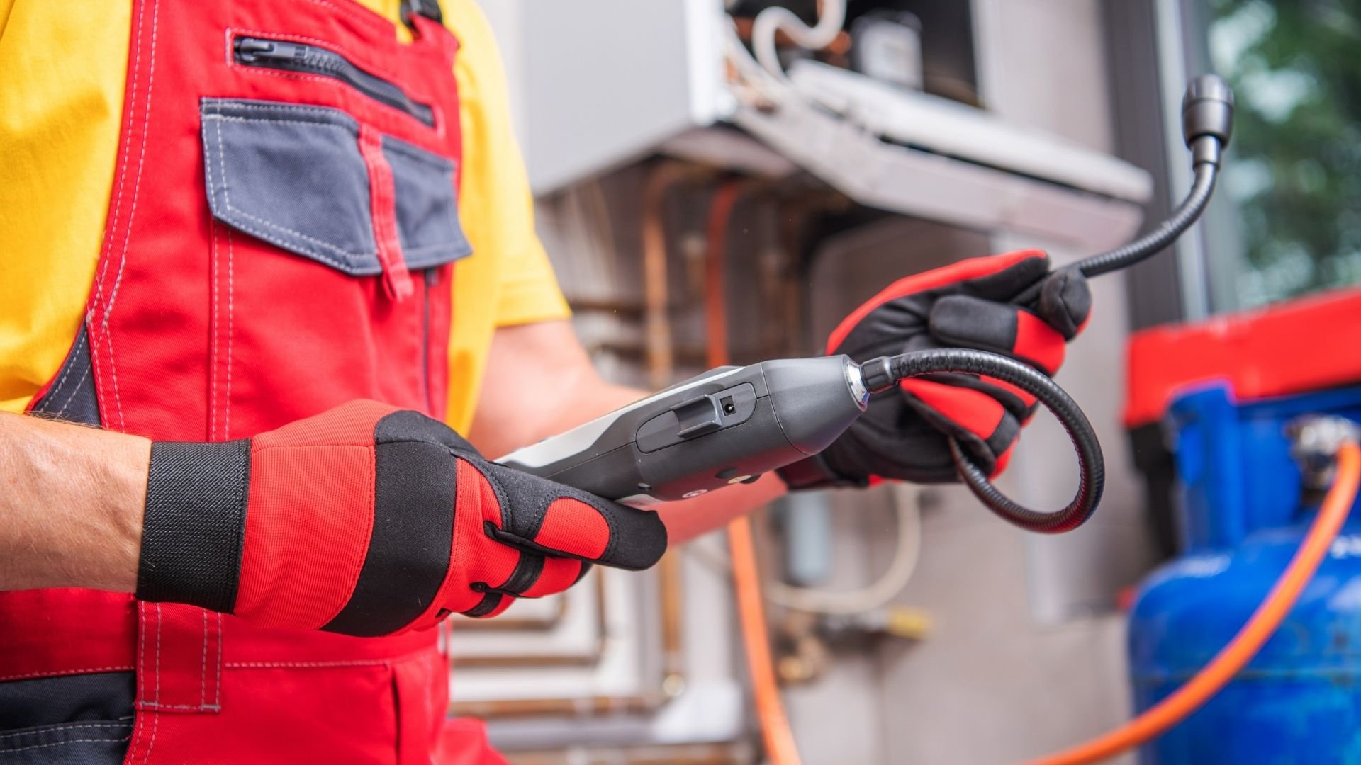 Worker in red and yellow uniform holding electric vehicle charging cable connector